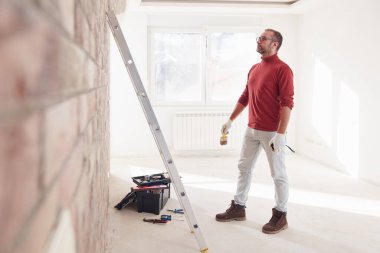 Yeni bir evde çalışan merdivenli tamirci elektrikçi..