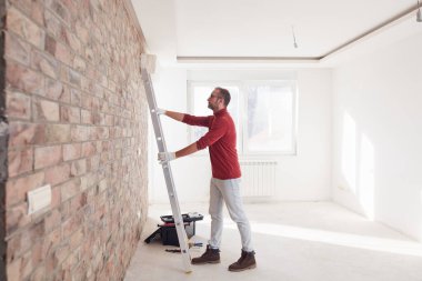 Yeni bir evde çalışan merdivenli tamirci elektrikçi..