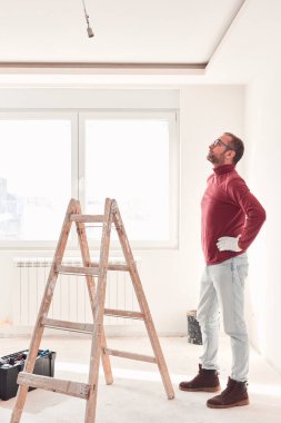 Yeni bir evde çalışan merdivenli tamirci elektrikçi..