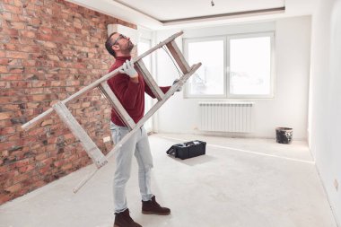 Yeni bir evde çalışan merdivenli tamirci elektrikçi..