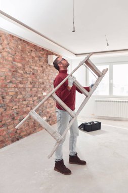 Yeni bir evde çalışan merdivenli tamirci elektrikçi..