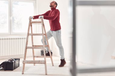 Yeni bir evde çalışan merdivenli tamirci elektrikçi..