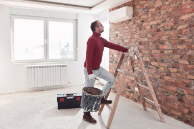 Yeni bir evde çalışan merdivenli tamirci elektrikçi..