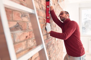 Handyman with spirit level working in a new home interior. clipart