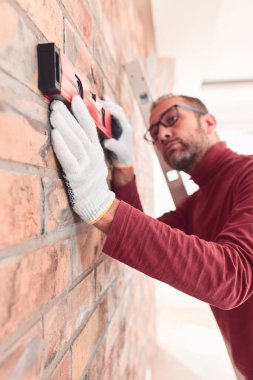 Handyman with spirit level working in a new home interior. clipart