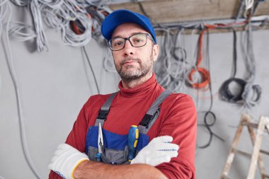 Bir inşaat sahasında kablo sistemi üzerinde çalışan elektrikçi..