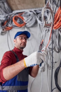 Bir inşaat sahasında kablo sistemi üzerinde çalışan elektrikçi..