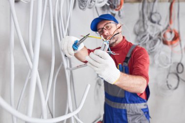 Bir inşaat sahasında kablo sistemi üzerinde çalışan elektrikçi..