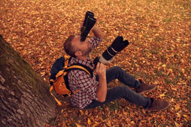 Dürbün ve kamera kullanan adam doğada kuşları ve hayvanları izliyor..