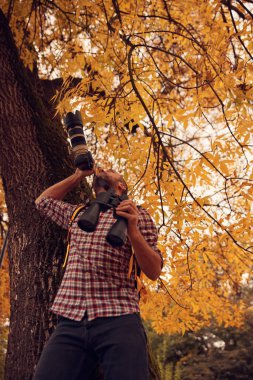 Man using binoculars and camera for bird and animal watching in nature. clipart