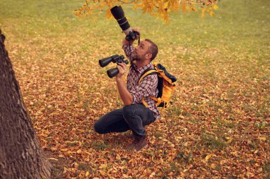 Dürbün ve kamera kullanan adam doğada kuşları ve hayvanları izliyor..