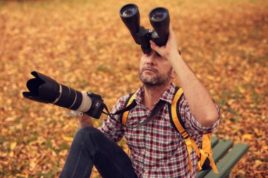 Dürbün ve kamera kullanan adam doğada kuşları ve hayvanları izliyor..