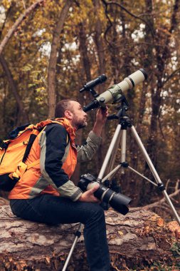 man using telescope for bird and animal watching in nature. clipart