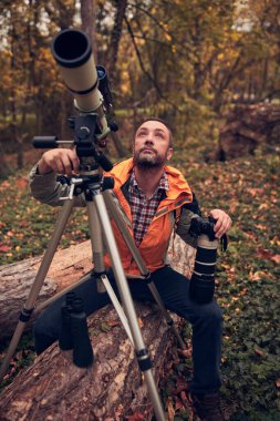 man using telescope for bird and animal watching in nature. clipart