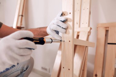 Yeni ahşap bir raf ve mobilya monte eden bir adam..