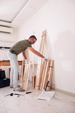 Yeni ahşap bir raf ve mobilya monte eden bir adam..