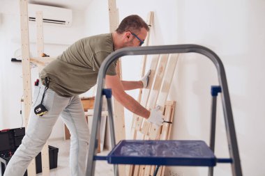 Yeni ahşap bir raf ve mobilya monte eden bir adam..