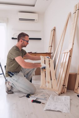 Yeni ahşap bir raf ve mobilya monte eden bir adam..