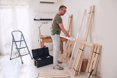 Yeni ahşap bir raf ve mobilya monte eden bir adam..