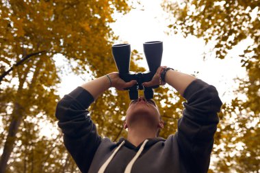 Kadın kuş gözlemlemek ve doğadaki diğer hayvanları gözlemlemek için dürbün kullanıyor..