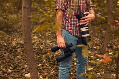 Dürbün ve kamera kullanan bir adam kuşları ve doğadaki diğer gözlemci hayvanları izliyor..