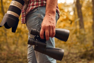 Dürbün ve kamera kullanan bir adam kuşları ve doğadaki diğer gözlemci hayvanları izliyor..