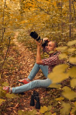 Dürbün ve kamera kullanan bir adam kuşları ve doğadaki diğer gözlemci hayvanları izliyor..