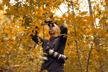 Dürbün ve kamera kullanan bir adam kuşları ve doğadaki diğer gözlemci hayvanları izliyor..