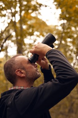 Dürbünü kuşları izlemek için kullanan adam ve diğer gözlemci hayvanlar doğada.