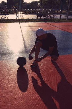 Adam halka açık bir sahada basketbol oynadıktan sonra duraksıyor.