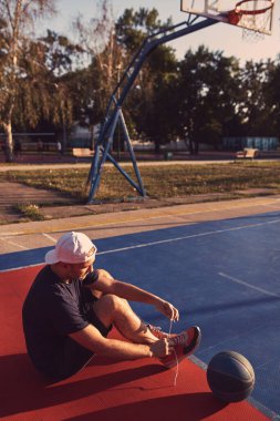 Adam halka açık bir sahada basketbol oynadıktan sonra duraksıyor.