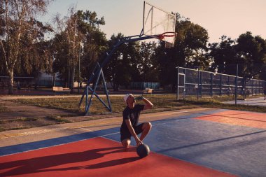 Adam halka açık bir sahada basketbol oynadıktan sonra duraksıyor.