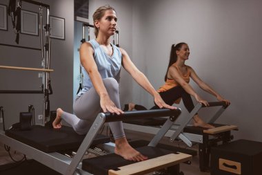 Young women exercising in a gym on pilates machines.