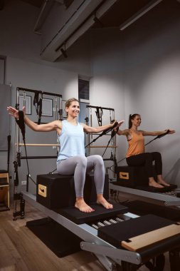 Young women exercising in a gym on pilates machines.