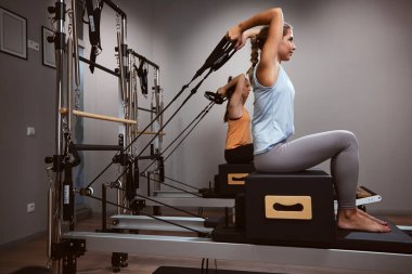 Young women exercising in a gym on pilates machines.