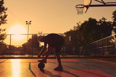 Halk sahasında basketbol topu olan bir adam..