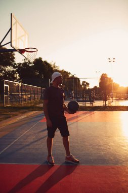 Halk sahasında basketbol topu olan bir adam..