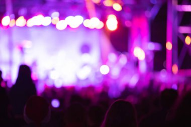 Sahne ışıkları olan, bulanık fotoğraflı konser kalabalığının siluetleri.