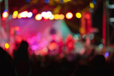 Sahne ışıkları olan, bulanık fotoğraflı konser kalabalığının siluetleri.