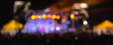 Sahne ışıkları olan, bulanık fotoğraflı konser kalabalığının siluetleri.