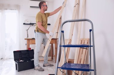 Yeni ahşap bir raf ve mobilya monte eden bir adam..