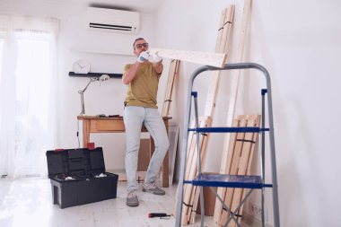 Yeni ahşap bir raf ve mobilya monte eden bir adam..