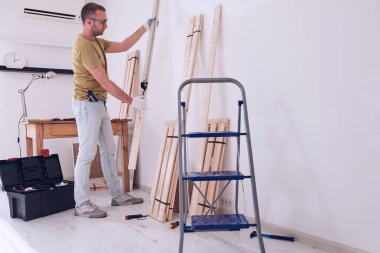 Yeni ahşap bir raf ve mobilya monte eden bir adam..