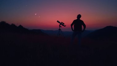 Astronom teleskopla yıldızlara, gezegenlere, aya ve gök cisimlerine bakıyor..