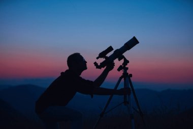 Gökbilimci teleskopla gökyüzüne bakıyor..