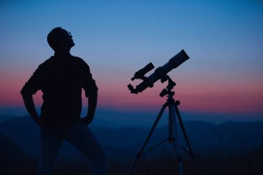 Gökbilimci teleskopla gökyüzüne bakıyor..