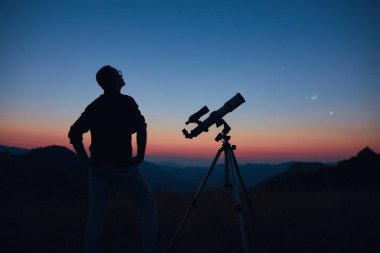 Yıldızlı gökyüzüne ve teleskopla hilal aya bakan bir astronom..