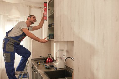 Tamirci dairedeki mutfak dolaplarını tamir ediyor..