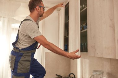 Tamirci dairedeki mutfak dolaplarını tamir ediyor..