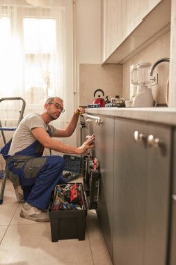 Tamirci dairedeki mutfak dolaplarını tamir ediyor..